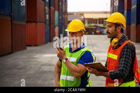 Two industrial workers are discussing the job planning in the shipping industry. Stock Photo