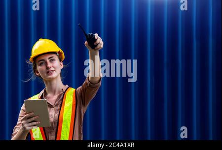 Female foreman is using walkie talkie and computer tablet to control work in industrial business Stock Photo