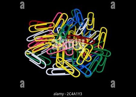 A pile of colourful paper clips isolated against a black background Stock Photo
