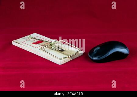 A wooden rodent trap and computer mouse on a red background Stock Photo