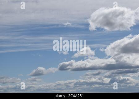 Various white and grey cloud formations against a blue sky. Stock Photo