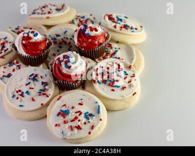 https://l450v.alamy.com/450v/2c4a38h/pile-of-sugar-cookies-covered-in-white-frosting-with-red-white-and-blue-sprinkles-and-mini-chocolate-cupcakes-with-red-and-white-frosting-with-star-s-2c4a38h.jpg