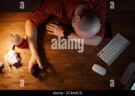 High angle view of drunk man sleeping at his workplace in front of computer Stock Photo