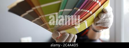 Builder in gloves shows color samples for repair Stock Photo