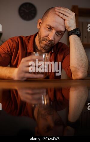 Frustrated mature man has life problems he sitting at the table and thinking about this and drinking alcohol Stock Photo
