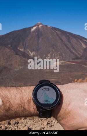 Runner checking progress on smart watch. Volcano on background Stock Photo