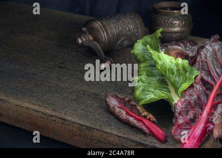 Fresh leaves of swiss chard in green and burgundy colors on a dark wooden background. Vintage style. Copy space Stock Photo