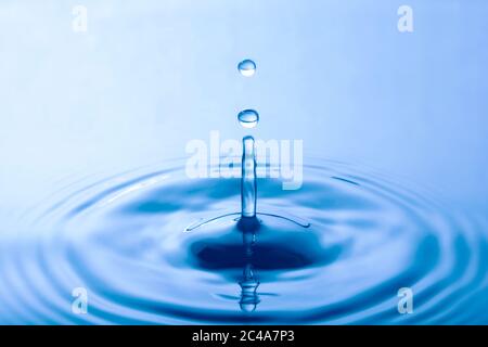 Water droplet falling impact with water surface. causing rings on water surface. Stock Photo