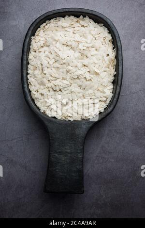 Raw Flattened Rice or Thick or thin Rice Flakes for Namkeen Chivda snacks or Aloo Poha for Indian Breakfast, served in a bowl Stock Photo