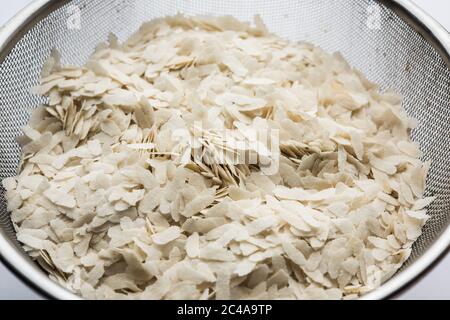 Raw Flattened Rice or Thick or thin Rice Flakes for Namkeen Chivda snacks or Aloo Poha for Indian Breakfast, served in a bowl Stock Photo