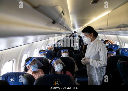 An air hostess of Buddha Air wearing a protective suit attends to passengers inside the aircraft during a mock safety drill to make necessary preparations for the resumption of domestic and international flights.Commercial flights to Nepal have been suspended since March 26th due to the risk of coronavirus infection. The government is preparing to open commercial flights as the risk of infection decreases. Stock Photo