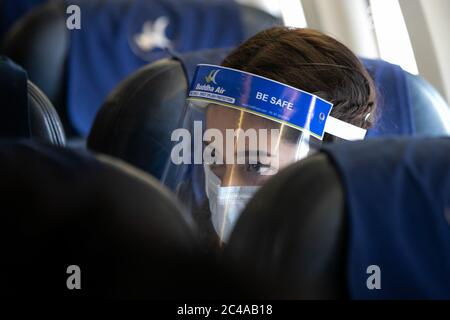 A female passenger in an aircraft of Buddha Air wearing a face mask and shield during a mock safety drill to make necessary preparations for the resumption of domestic and international flights.Commercial flights to Nepal have been suspended since March 26th due to the risk of coronavirus infection. The government is preparing to open commercial flights as the risk of infection decreases. Stock Photo