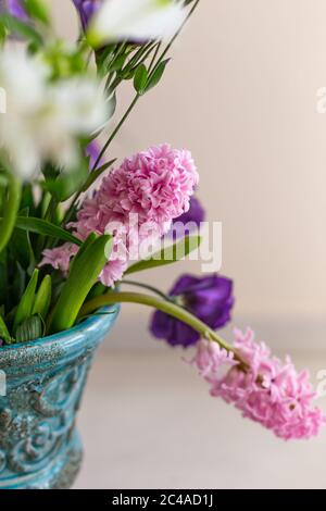 Vertical image of pink hyathintus in a turquoise rustic vase against light gray background. Negative space. Stock Photo