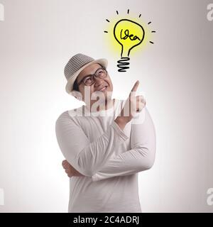 Young Asian man looked happy thinking and looking up, having good idea. Half body portrait against white wall with copy space Stock Photo