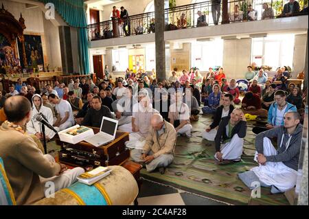 Krishna followers sitting on a floor and listening to guru preaching in a temple Stock Photo
