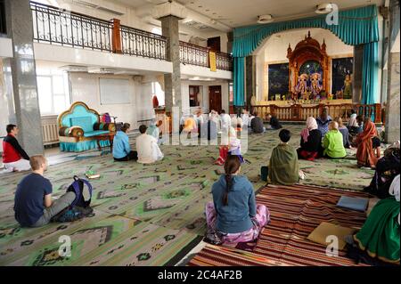 Krishna followers sitting on a floor and listening to guru preaching in a temple Stock Photo