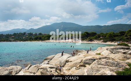 Halkidiki, Greece, June 27 2017:  People at The famous  rocky beach of vourvourou beach, with turquoise water at Sithonia halkidhiki Greece Stock Photo
