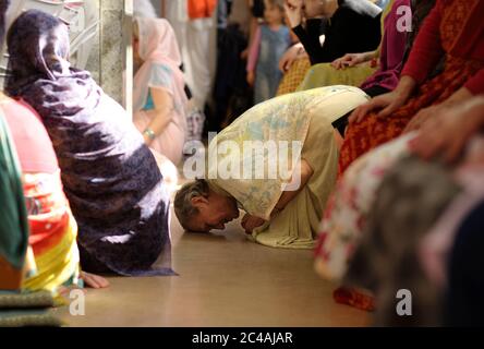Krishna female follower kneeling on a floor and praying in a temple Stock Photo