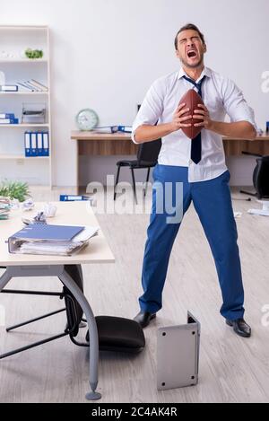 Young employee throwing rugby ball in the office Stock Photo