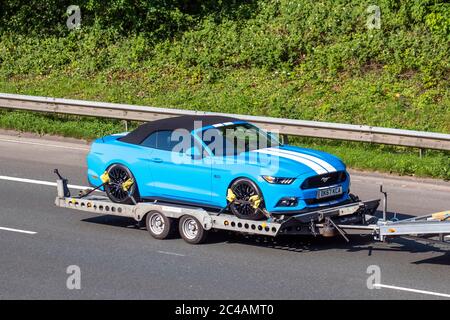 2017 blue white Ford Mustang GT V8;  Vehicular traffic on tow, moving vehicles, cars driving vehicle towing car trailer on UK roads, motors, motoring on the M6 motorway Stock Photo