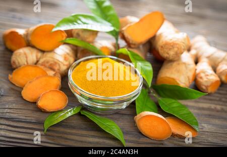 Turmeric powder and turmeric roots on the wooden table Stock Photo