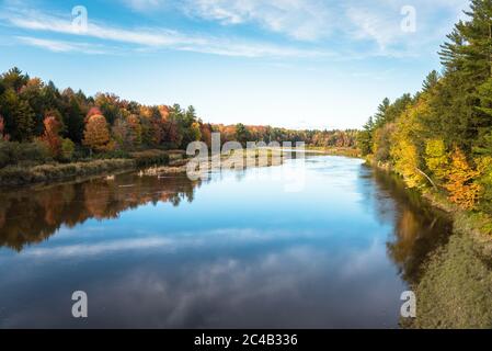 River through a forest at the peak of autumn colours. Tranquil scene. Stock Photo