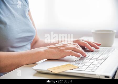 Cropped image of a woman using a laptop for shopping online. A credit card is visibel on the keyboard. Stock Photo