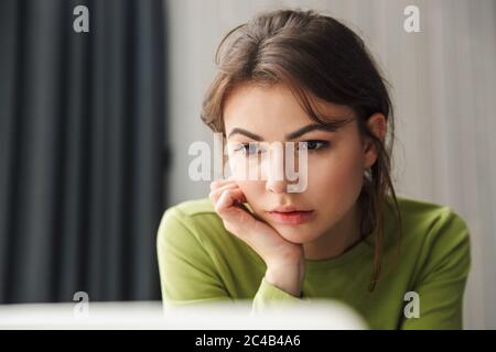 Photo closeup of focused brunette beautiful woman using laptop in cozy room at home Stock Photo
