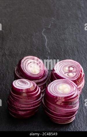 Sliced  red onion rings on black stone background Stock Photo