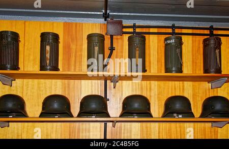 black helmets and canisters on shelf, German bunker interior, living quarters, paneled wall, Atlantic Wall Open Air Museum; WWI and II defense; milita Stock Photo