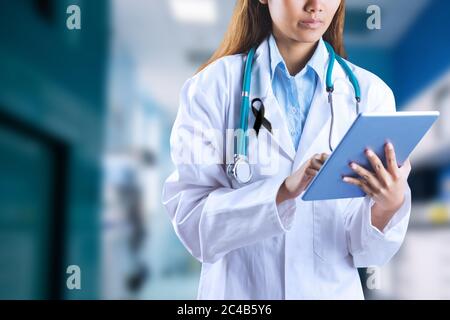 Mid section of lady doctor with black ribbon on robe taking notes in the hospital Stock Photo