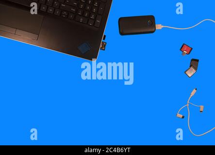 Sd card battery supply cords lap top and flat lay on a blue desk top. showing personal data storage gadgets with open space for customer product place Stock Photo