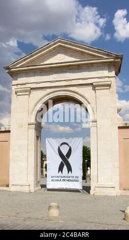 Puerta de Madrid (Madrid Arch) in Alcala de Henares with a banner remembering the dead from Covid-19 black ribbon design Madrid Spain Stock Photo