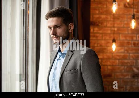 Thinking businessman in the office looking through the window. Stock Photo