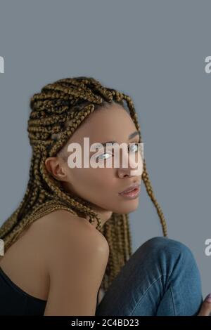 Disappointed young African American woman sitting, holding her knee Stock Photo