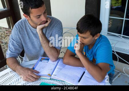 Young man helping his younger brother with homework Stock Photo