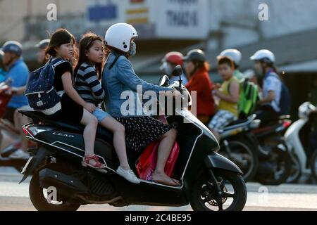 Mother and children riding motorbile on the way to school Stock Photo