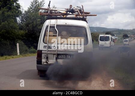 Old minibus emitting black smoke on road Stock Photo