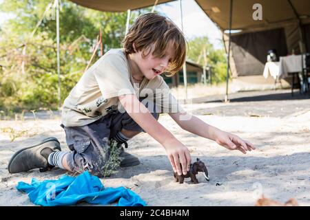 A six year old boy playing with toys in a tented camp, Nxai Pa, Botswana Stock Photo