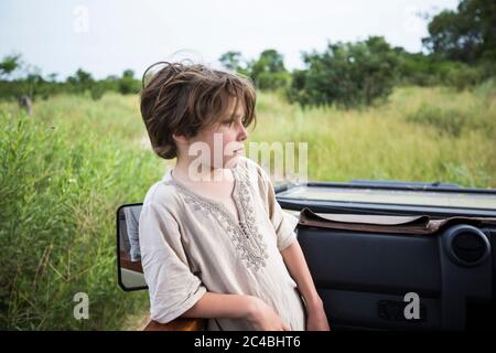 Six year old boy standing looking around the landscape in a safari jeep. Stock Photo