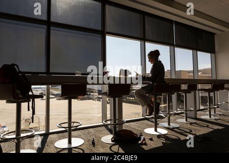 A mature woman, female executive seated using a laptop in an airport departure lounge Stock Photo