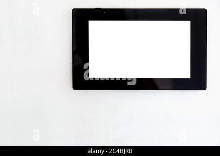 tablet with black case and white blank screen front view on white wall background with copy space for text, display of smart home control device. Stock Photo