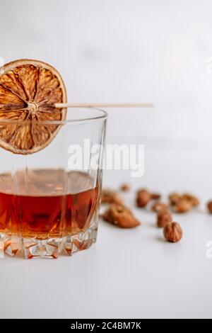 Strong alcohol whisky in a glass cup with a slice of dried orange and nuts. Stock Photo