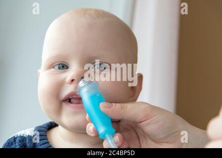 Mom cleans baby's nose from mucus using a nasal aspirator Stock Photo