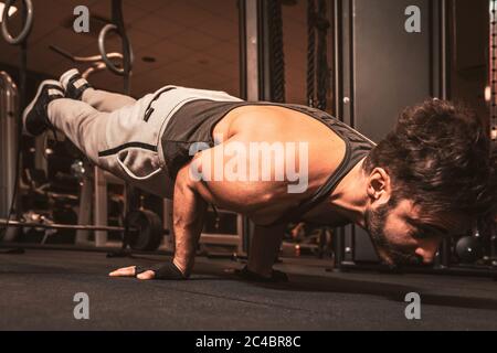 a bearded sporty man in the gym is doing yoga exercises pungu mayurasana wounded peacock posture 2c4br8c