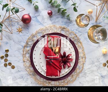 Christmas table setting with gold utensils in folded textile napkin and fresh eucalyptus on marble background. Flat lay on table with golden cutlery, Stock Photo