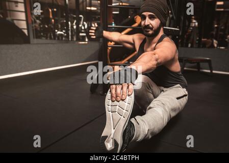 Man practicing yoga in gym, sitting in paschimottanasana exercise. Seated forward bend pose. Yoga mental benefits. Stock Photo