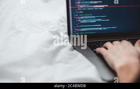 Female programmer writes program code on a computer laptop in the bed .  Stock Photo