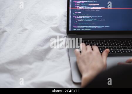 Female programmer writes program code on a computer laptop in the bed .  Stock Photo
