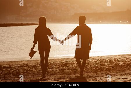 Young couple enjoying vacation on tropical beach - Romantic lovers silhouette having fun together on summer holidays Stock Photo